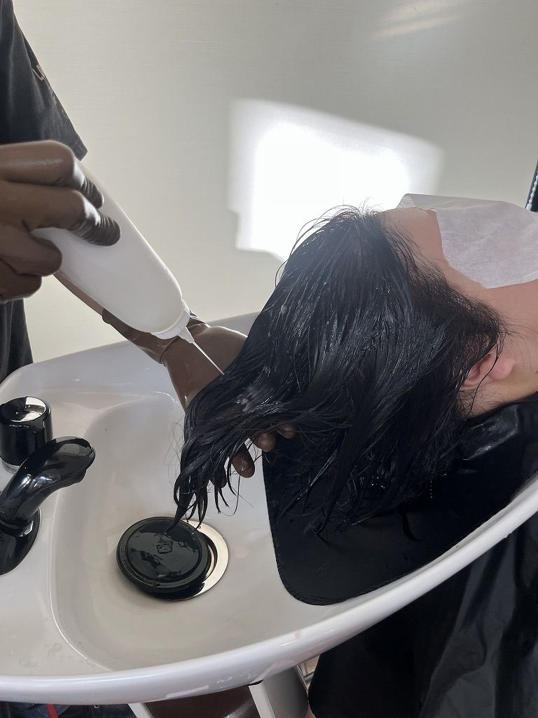 髪質改善トリートメントをシャンプー台で塗布している様子
