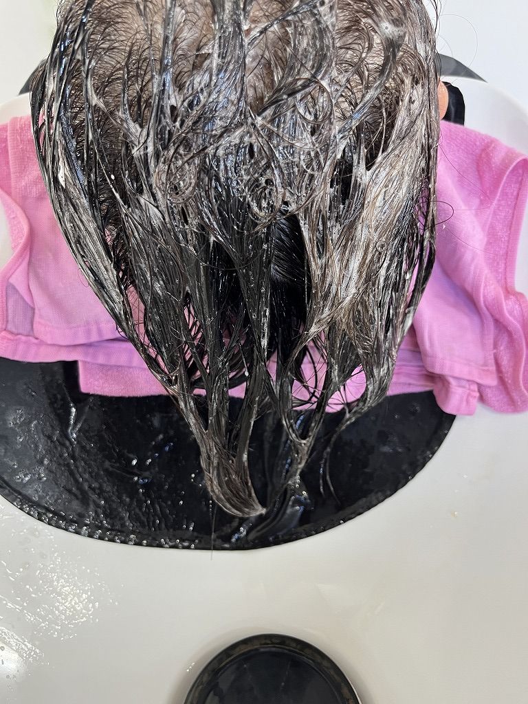 シャンプー台でトリートメントを塗布している様子