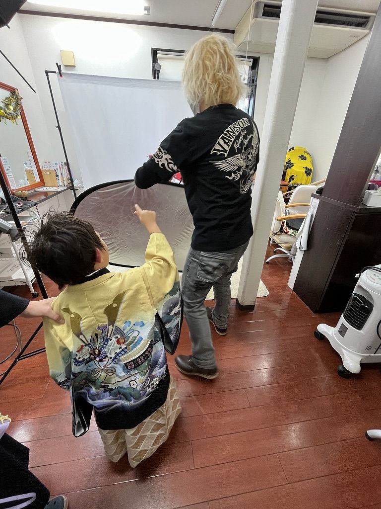 撮影中にカメラマンにイタズラしようとしている男の子と、その手をそっと押さえるお母さん