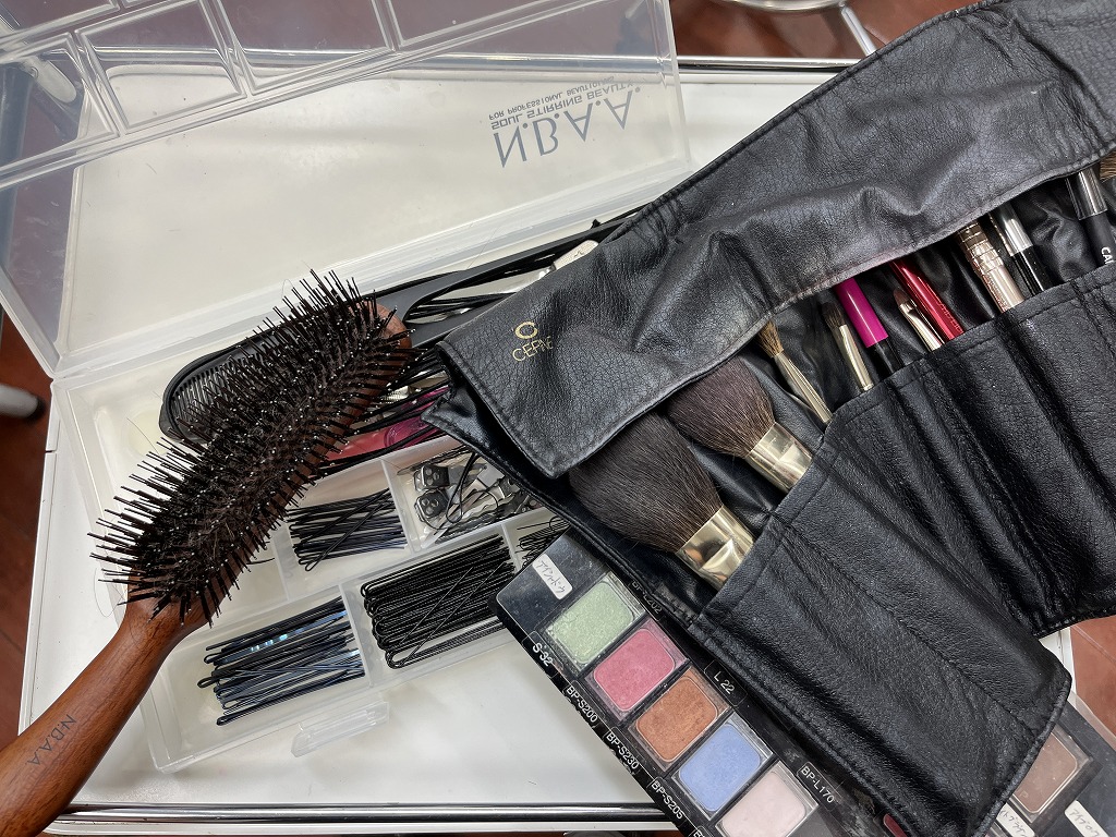 ヘアメイク用のブラシやピン類、メイク道具の写真