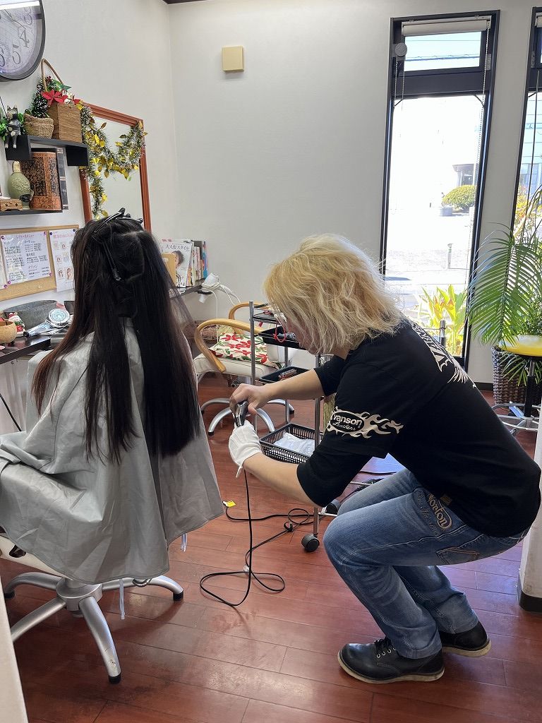 縮毛矯正のアイロン施術中の様子・ロングヘアの中間から毛先を丁寧に伸ばしている写真