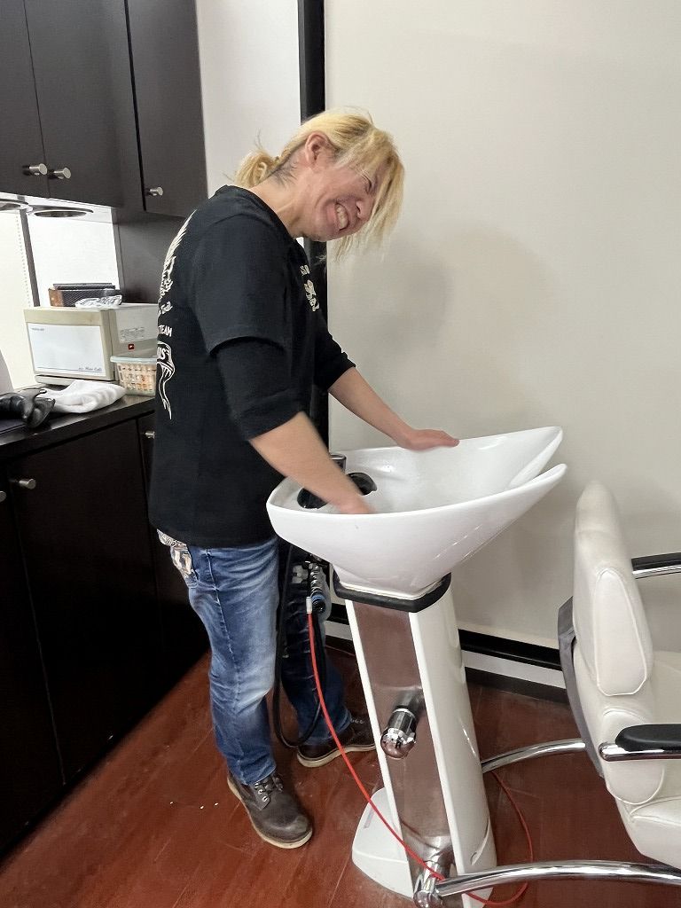 タイシがシャンプー台の清掃をしている様子。施術環境を整えるための営業後ルーティン