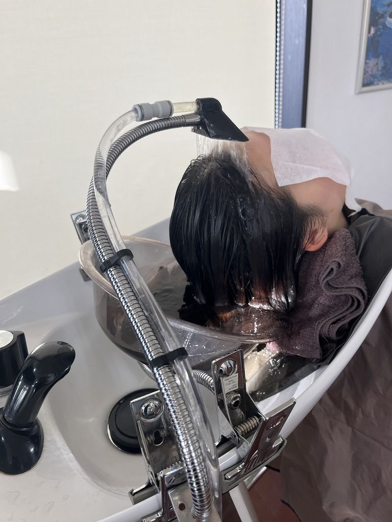 ハナヘナ放置後にシャンプーをして炭酸頭浸浴を行っている写真。頭皮と髪にうるおいを与えるケア工程。