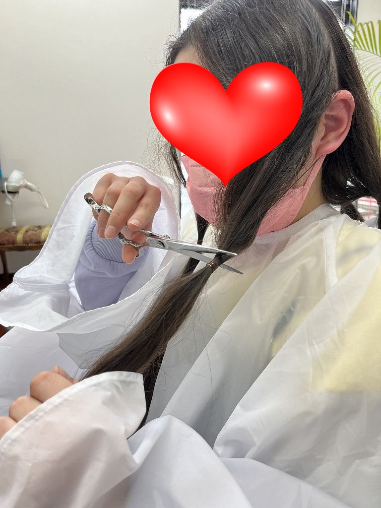 お客様自身でヘアドネーションの毛束をカットしている様子