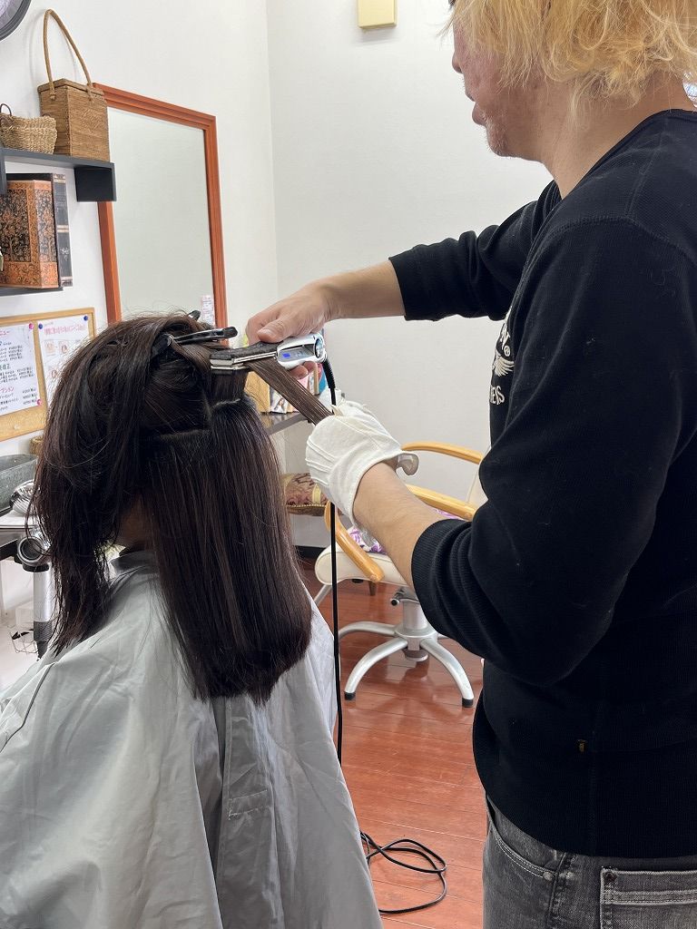 縮毛矯正のアイロン施術中。毛束を丁寧に伸ばしている様子
