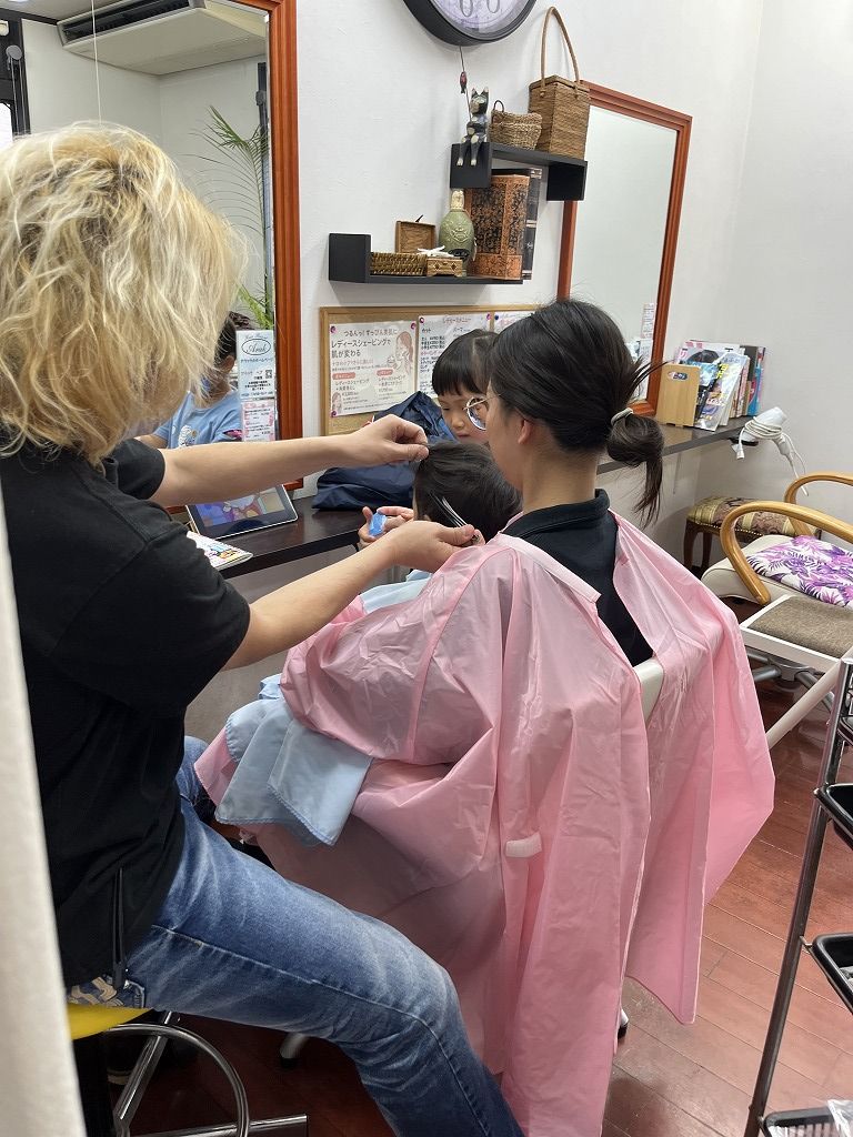 お母さんに抱っこされながら美容室でカットしている小さなお子さんの様子