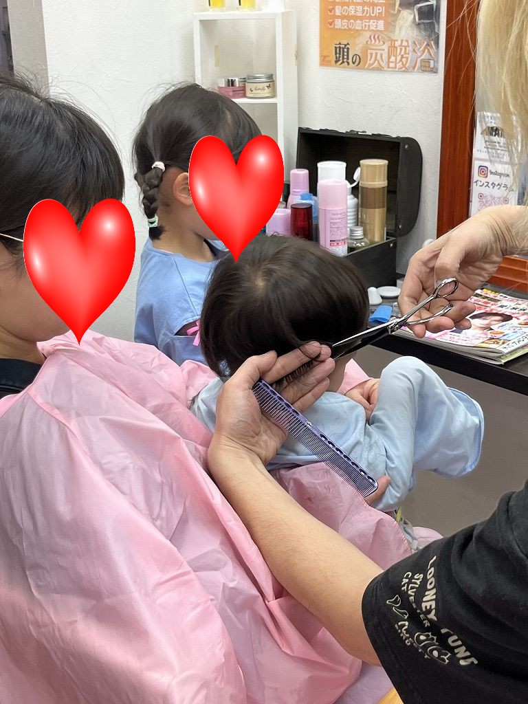 小さなお子さんの髪を安全に注意しながらハサミでカットしている様子