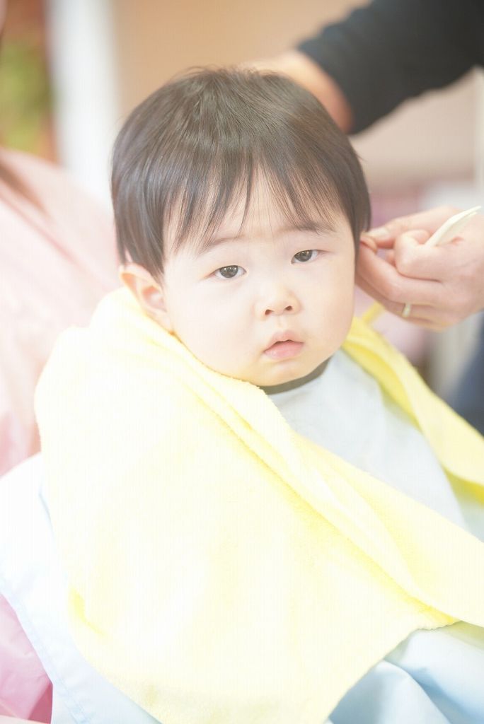 お母さんに抱っこされながら1歳の男の子がキッズカットをしている様子