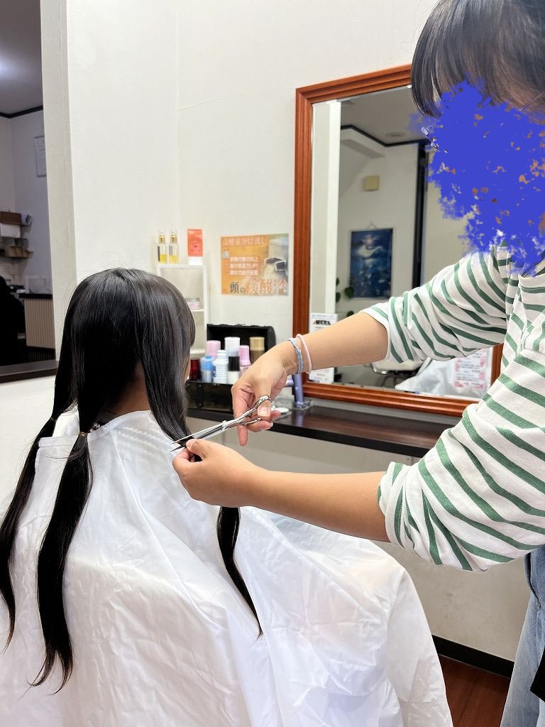 お母さんがヘアドネーションの最初の毛束をカットしている様子