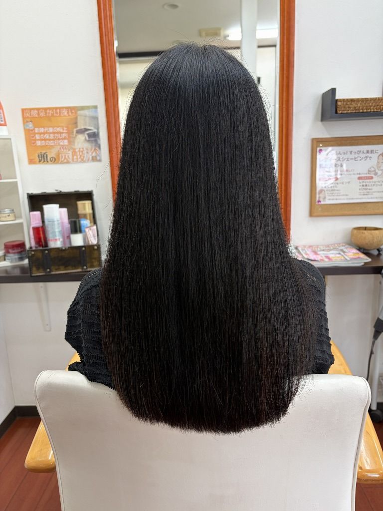 強めの波状毛を縮毛矯正で整えたロングヘアの後ろ姿