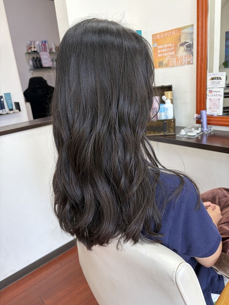 5cmカットと低めのレイヤーを入れてコテで巻いたロングヘアの仕上がりを斜め後ろから見た写真