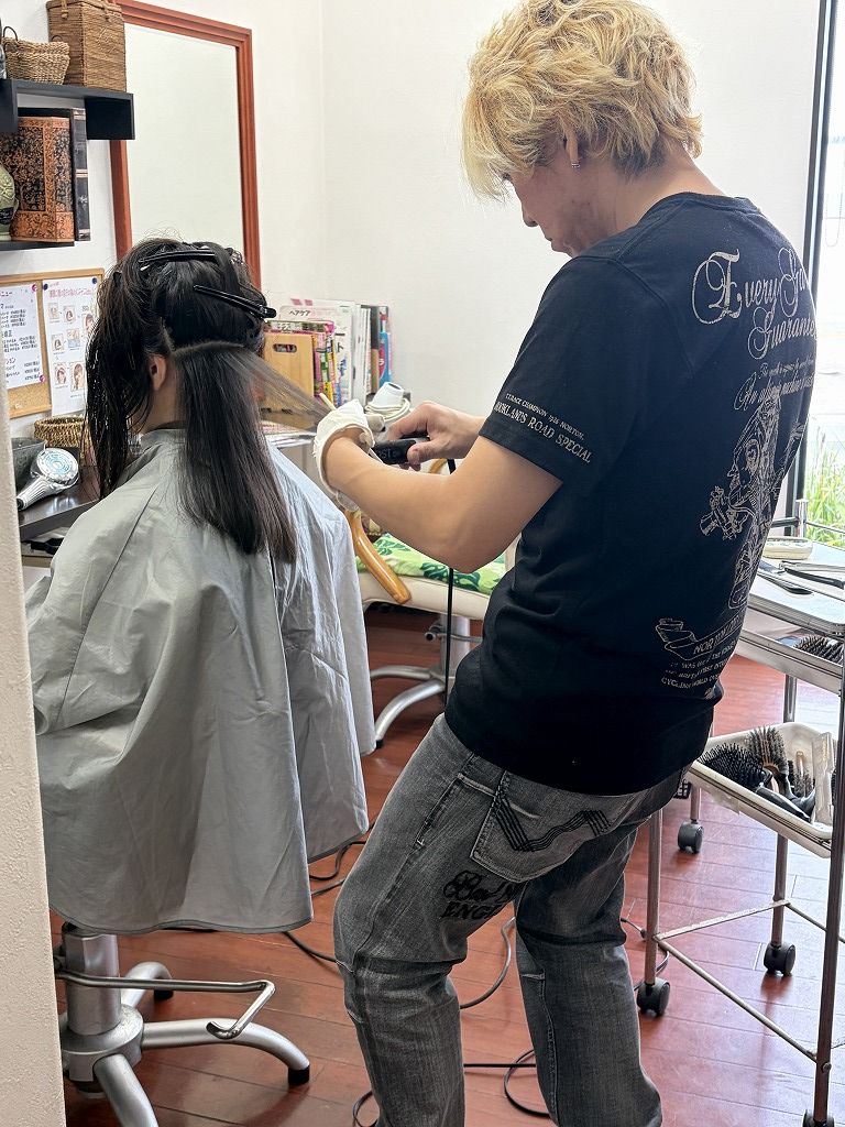 細毛と軟毛のロングヘアに縮毛矯正のアイロン施術をしている様子