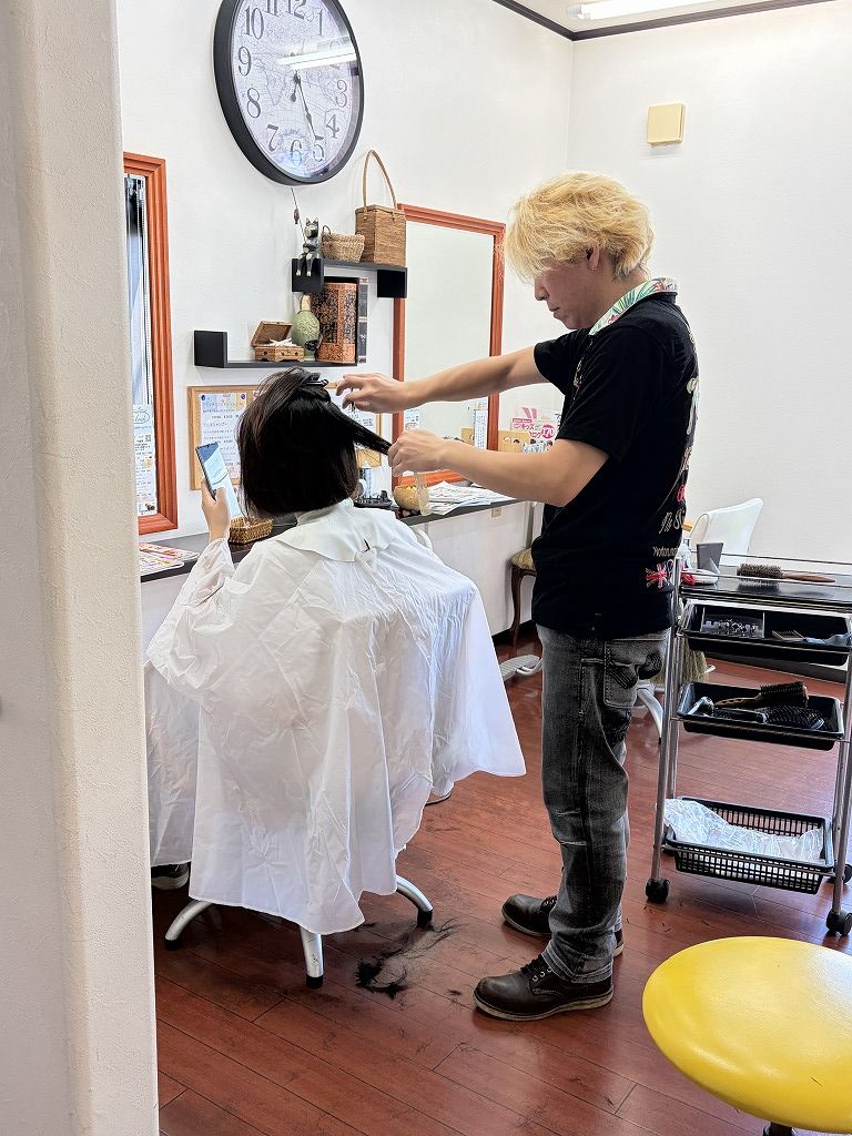 HairResort Arakの美容フロアで女性ゲストをカットする美容師の大志