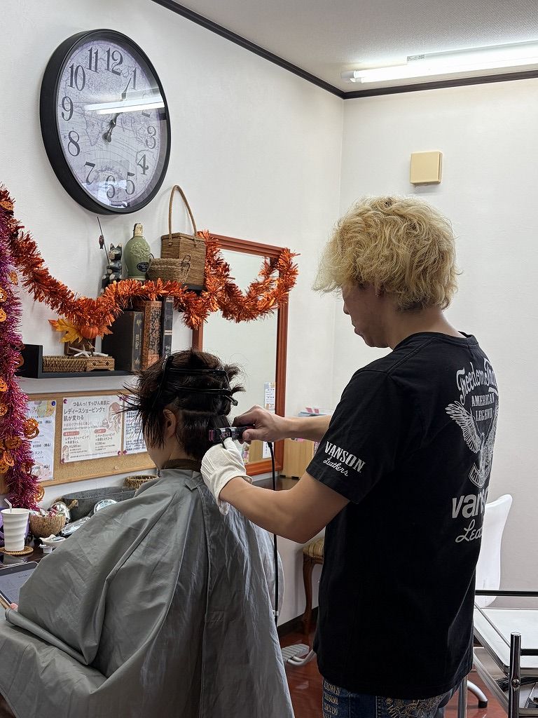 ショートヘアのお客様に縮毛矯正のアイロン施術をしている美容師の仕事風景
