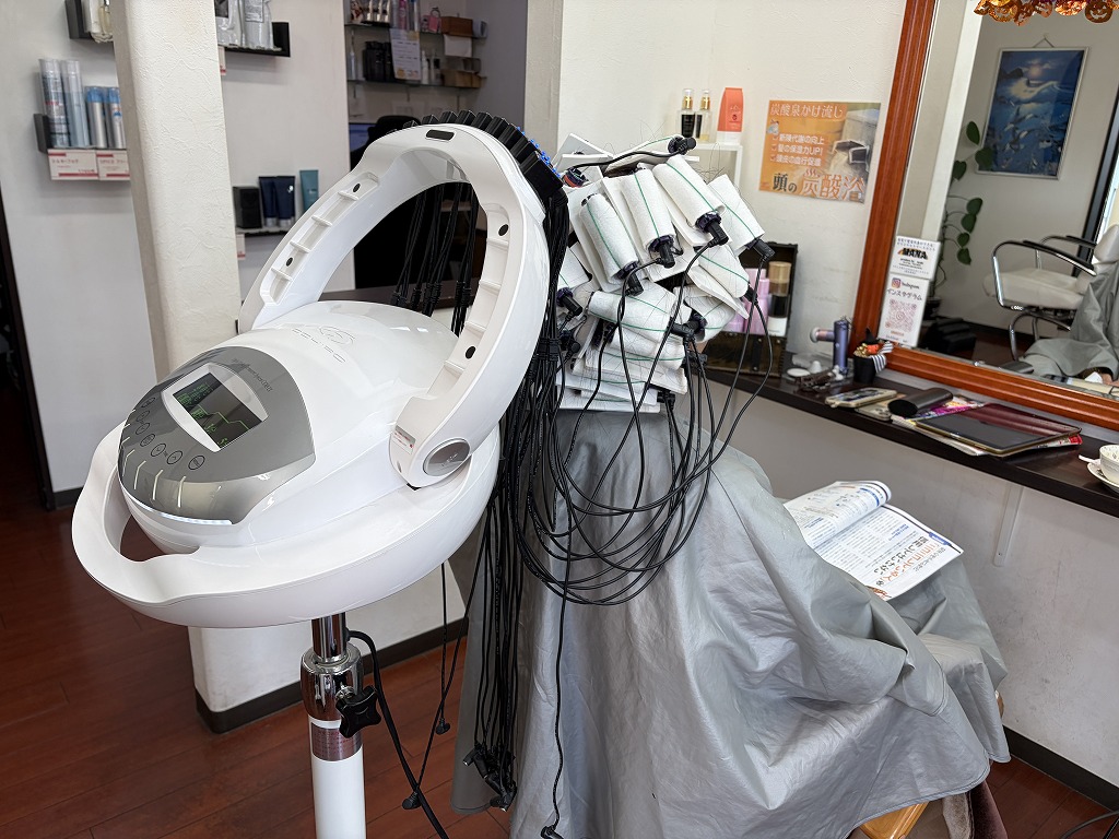 ロングヘアにデジタルパーマのロッドを巻き加温している施術中の様子