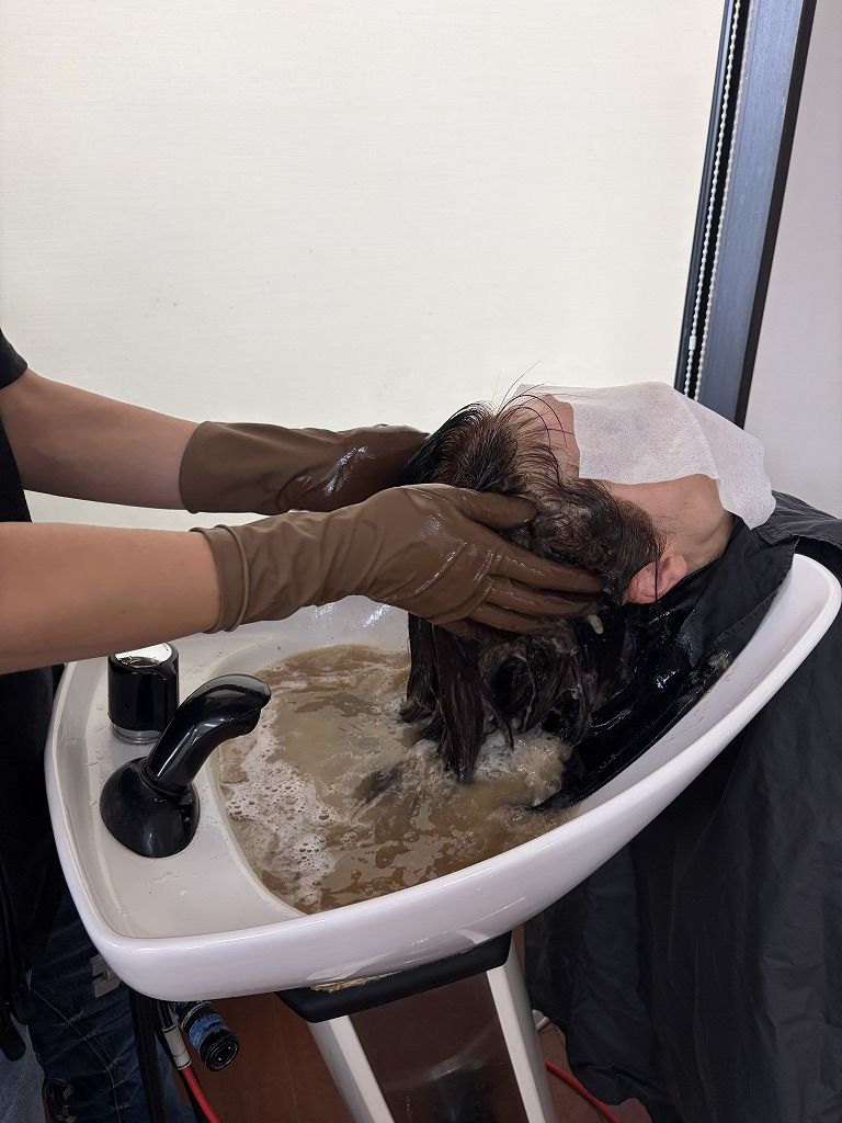 ヘアカラーの放置後にシャンプー台でカラー剤を乳化している施術風景