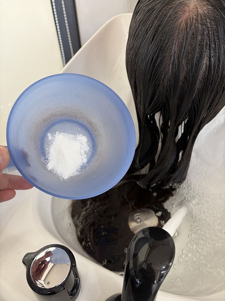 アルギニンの粉末をシャンプー台のお湯に溶かして髪の前処理に使用する工程